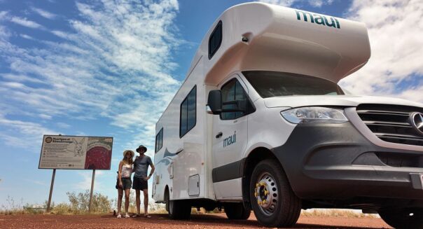 Stel staat naast Maui River om bord te lezen onderweg naar Broome