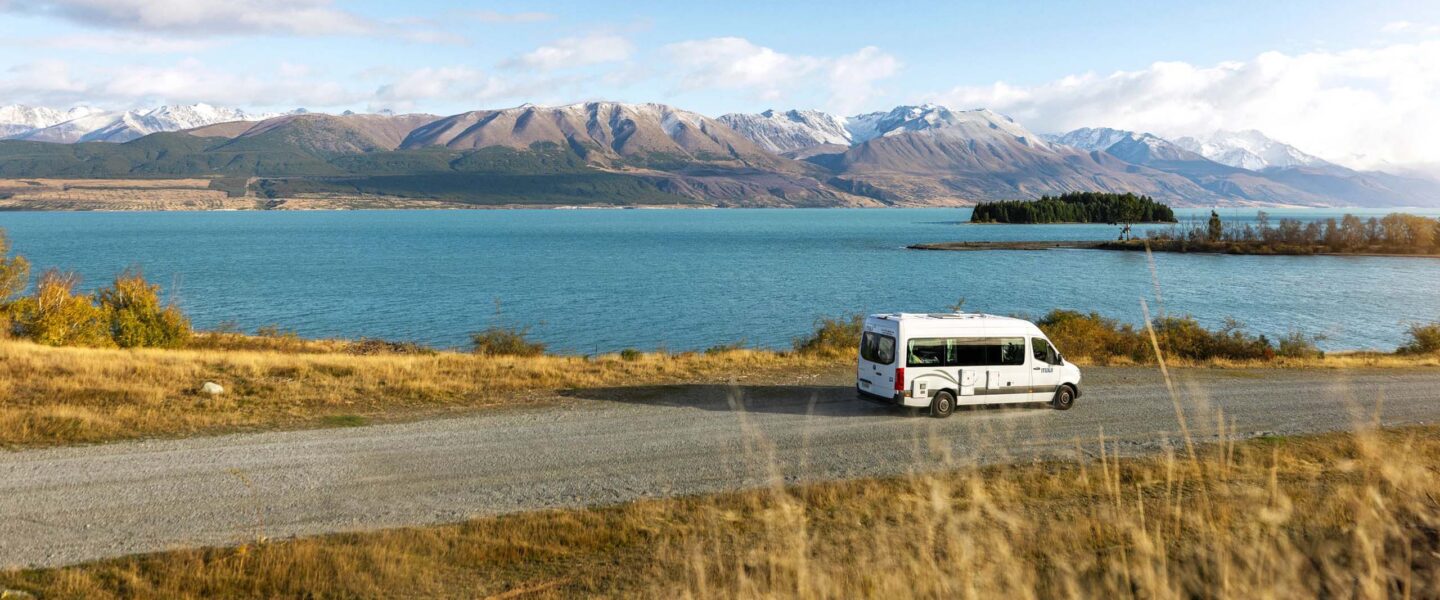 De Maui Ultima rijdt over een weg langs Lake Wanaka met uitzicht op de bergen