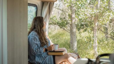Vrouw zit relaxed met een kop thee in de Britz Venturer camper in Nieuw-Zeeland