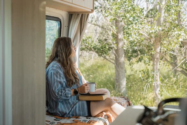 Vrouw zit relaxed met een kop thee in de Britz Venturer camper in Nieuw-Zeeland