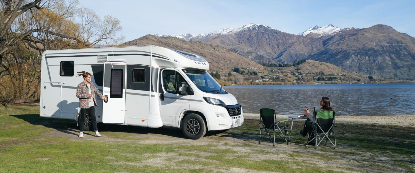 Een stel is aan het wild kamperen met de Britz Odyssey aan een meer
