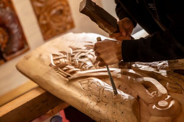 Een Maori maakt houtsnijwerk in Rotorua