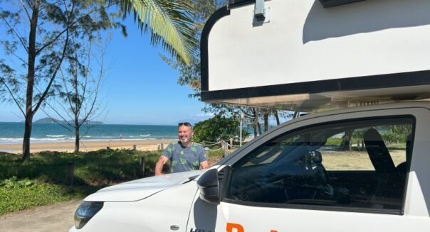 Peter Kramer staat bij de Britz Maverick aan het strand bij Mission Beach in Queensland