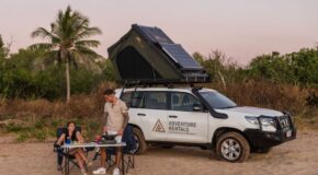 Stel zit aan tafel voor de Adventure Rentals Toyota Prado 4WD camper met het dak omhoog