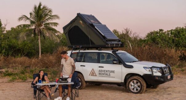 Stel zit aan tafel voor de Adventure Rentals Toyota Prado 4WD camper met het dak omhoog
