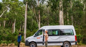 Apollo Endeavour staat geparkeerd in een bos in Australië, vrouw staat bij de open deur